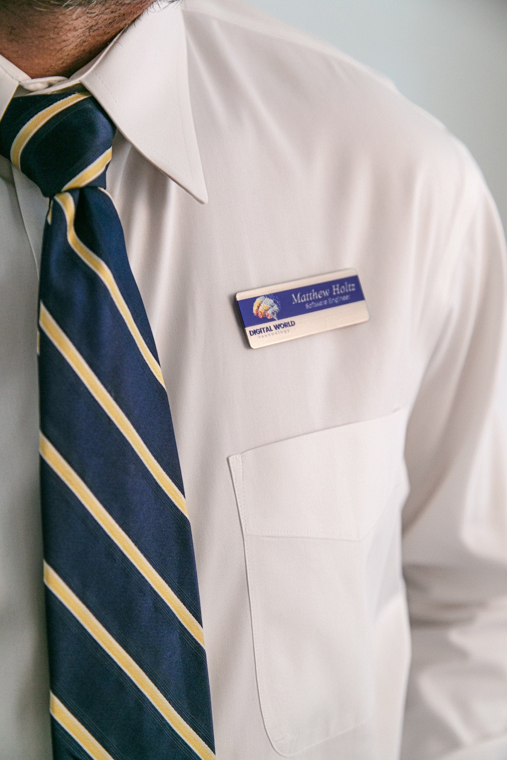 a close up of a man wearing a white shirt and blue and yellow striped tie